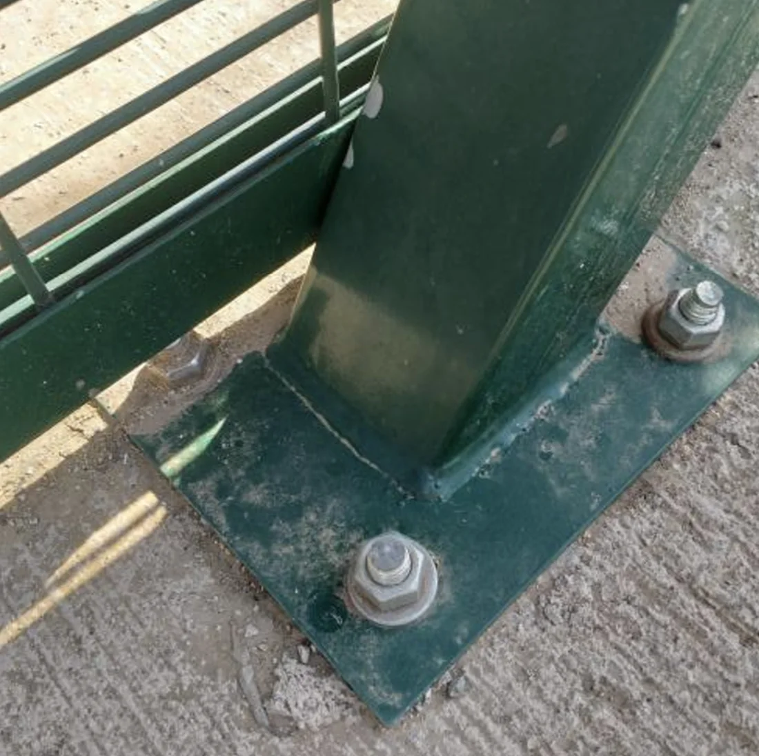 Detalle de anclaje de poste metálico verde al suelo